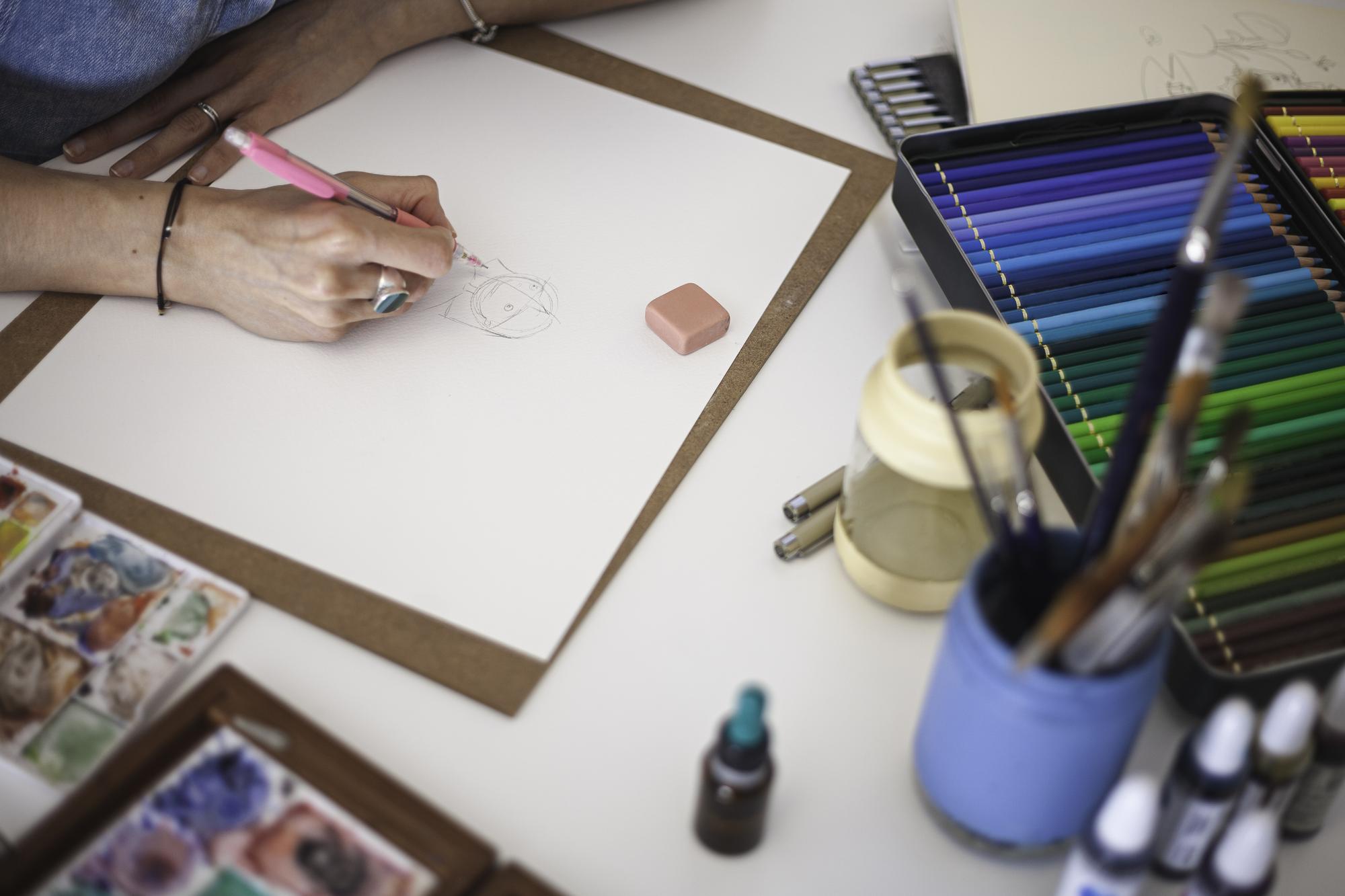 Artisan selecting threads and sketching pattern